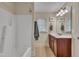 Bathroom features a shower-tub combo, vanity with dark cabinets and granite countertops with a bright natural-light window at 124 Mantle Dr, Clayton, NC 27527