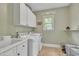 Bright laundry room with sink, washer, dryer, and storage cabinets at 124 Mantle Dr, Clayton, NC 27527