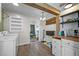 A bright laundry room featuring wood beam accents, a washer, dryer, shelving, and wood-look floors at 1329 Mebane St, Burlington, NC 27217