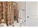 Bathroom with a tiled shower and floral shower curtain, a standard toilet, and a white door at 149 Country Mill Way, Fuquay Varina, NC 27526