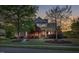 Charming brick home featuring a well-manicured front yard with lush landscaping and mature trees at dusk at 149 Country Mill Way, Fuquay Varina, NC 27526