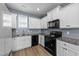 Well-lit kitchen featuring white cabinets, granite countertops, and modern black appliances at 166 Yellow Jacket Rdg, Clayton, NC 27520