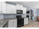 An open concept kitchen showcasing white cabinetry, black appliances and sleek granite countertops at 166 Yellow Jacket Rdg, Clayton, NC 27520