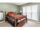 Cozy bedroom featuring a wooden bed frame, natural light from the windows, and carpet flooring at 1850 Crissy Ln, Graham, NC 27253