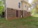 Exterior view of house featuring a brick foundation, tan siding, and an exterior door at 1850 Crissy Ln, Graham, NC 27253