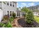 Backyard with manicured beds, lush green plantings, a patio, and partial views of the home's exterior at 201 Lakewater Dr, Cary, NC 27511