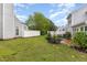 Backyard with lush green plantings, manicured beds, a patio, and partial views of the home's exterior at 201 Lakewater Dr, Cary, NC 27511