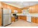 Bright kitchen with stainless steel refrigerator and oven, oak cabinets, and a view into dining room at 201 Lakewater Dr, Cary, NC 27511