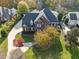 Stunning aerial view of a red brick home with a well-manicured lawn and mature trees in vibrant autumn colors at 204 Oxford Mill Ct, Cary, NC 27518