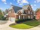 Brick home showcasing a three-car garage, lush lawn, and dormer windows at 204 Oxford Mill Ct, Cary, NC 27518