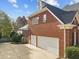 A brick house featuring a three-car garage, basketball hoop, and mature landscaping at 204 Oxford Mill Ct, Cary, NC 27518