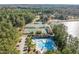 Aerial view showcasing tennis courts, a swimming pool, clubhouse, and parking lot surrounded by mature trees and a lake at 222 Kelso Ct, Cary, NC 27511