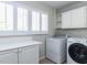 Functional laundry room with a white washer, dryer, counters, and storage at 222 Kelso Ct, Cary, NC 27511