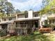 A charming rear exterior featuring a deck, screened porch, and beautifully landscaped yard with mature trees and flowering shrubs at 222 Kelso Ct, Cary, NC 27511