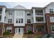 Three-story condo building with brick facade and multiple balconies, complemented by vibrant landscaping at 224 Eyam Hall Ln, Apex, NC 27502