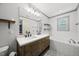 A bathroom features double sinks, modern lighting, a soaking tub, and stylish tile flooring, enhancing the spa-like feel at 301 Marsh Landing Dr, Holly Springs, NC 27540
