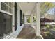 Side angle of front porch with wood floors and white pillars, showcasing landscaping and nearby homes at 301 Marsh Landing Dr, Holly Springs, NC 27540
