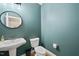 A convenient powder room features a pedestal sink, a round mirror, and a toilet, perfect for guests at 301 Marsh Landing Dr, Holly Springs, NC 27540