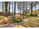 Serene backyard with mature trees, flower beds, and a rock drainage feature, creating a peaceful outdoor oasis at 3037 Freeman Farm Way, Rolesville, NC 27571
