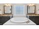 Modern bathroom featuring dual sinks, granite countertops, a tub, and large mirrors at 3037 Freeman Farm Way, Rolesville, NC 27571