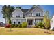 Charming two-story home with a covered front porch, stone accents, and a professionally landscaped front yard at 3037 Freeman Farm Way, Rolesville, NC 27571