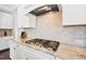 Close up of a well-lit kitchen features granite countertops, white cabinets, tile backsplash, and stainless steel range at 3037 Freeman Farm Way, Rolesville, NC 27571