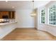 Open dining area with hardwood floors adjacent to the kitchen, featuring a modern chandelier and large windows at 3608 Burwell Rollins Cir, Raleigh, NC 27612