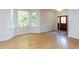Bright, empty living room with hardwood floors, bay windows, and a decorative front door with side windows at 3608 Burwell Rollins Cir, Raleigh, NC 27612