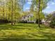 Expansive backyard showing the white home, mature trees, deck, patio, and well-kept lawn at 3612 Darwin Rd, Durham, NC 27707