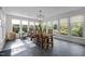 Dining room with large windows, rustic wooden table, modern chandelier, and stone tile flooring at 3612 Darwin Rd, Durham, NC 27707