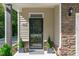Stylish entryway featuring a black screen door, stone accents, manicured greenery, and contemporary design at 3667 Durwood Ln, Raleigh, NC 27604