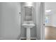 Charming powder room featuring pedestal sink, decorative mirror, light gray paint, and wood look floor at 3667 Durwood Ln, Raleigh, NC 27604