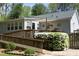 Back exterior view shows a home with a ramp, wooden deck, landscaping, and flowering plants at 38 Maple Cir, Pittsboro, NC 27312