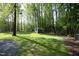 Large backyard with mature trees, grass lawn, utility shed, and gravel area at 38 Maple Cir, Pittsboro, NC 27312