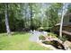 Large backyard features a gravel patio, pond with waterfall, well-manicured lawn, and mature trees at 38 Maple Cir, Pittsboro, NC 27312