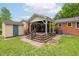 Backyard of a brick home with a covered wood deck and dining set, plus a storage shed and lawn at 3913 Vesta Dr, Raleigh, NC 27603