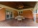 Covered deck with ceiling fan and dining set, adjoining a brick home with blue trim doors and windows at 3913 Vesta Dr, Raleigh, NC 27603