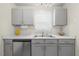 Close-up of kitchen showcasing grey cabinetry, stainless steel sink and marble countertops at 42 Riverwalk Ter, Durham, NC 27704