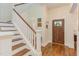Elegant foyer with hardwood floors, staircase, and view of front door and colorful artwork at 43 Turtle Point Bnd, Chapel Hill, NC 27516