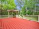 Large red deck with attached gazebo, surrounded by mature trees and landscaping at 5504 Cumberland Plain Dr, Raleigh, NC 27616