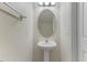 Stylish half bathroom featuring a modern pedestal sink, oval mirror, and neutral color scheme at 5801 Forest Point Rd, Raleigh, NC 27610