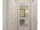 Hallway view to the bathroom with green striped wallpaper, tiled flooring and a framed mirror at 605 Glen Eden Dr, Raleigh, NC 27612