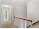 Hallway with wooden railing leading to a bedroom featuring patterned curtains and natural light at 605 Glen Eden Dr, Raleigh, NC 27612
