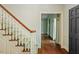 Carpeted staircase with wood railing leading to a room with large windows with floral patterned curtains at 605 Glen Eden Dr, Raleigh, NC 27612