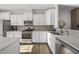 A modern kitchen showcases white cabinetry, stainless steel appliances, light countertops, and wood-look flooring at 6511 Academic Ave, Raleigh, NC 27616