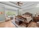 Spacious primary bedroom offers a tray ceiling, hardwood floors, a ceiling fan, and large windows at 6512 Southern Times Dr, Raleigh, NC 27603