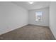 A minimalist bedroom featuring neutral walls and carpet and light-filled windows at 7205 Tillage Rd, Mebane, NC 27302