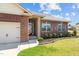 A view of the red brick exterior with a well-manicured flower garden surrounding the front door at 8 Pal Ct, Benson, NC 27504