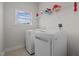 Neat laundry room with modern, white appliances, storage shelves, and a bright window for natural light at 8 Pal Ct, Benson, NC 27504