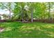 Lush, green backyard with mature trees providing shade and a large grassy area, perfect for outdoor activities at 8005 Somerdale Dr, Durham, NC 27713
